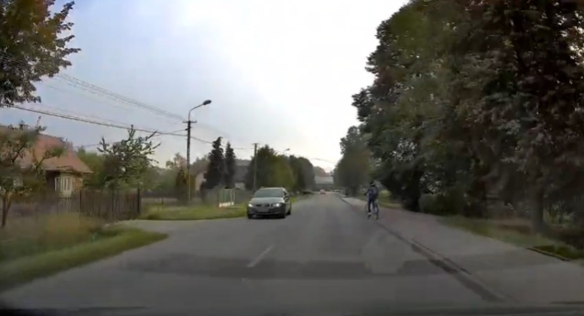 Zdjęcie przedstawia moment, w którym dziecko zaczyna zjeżdżać z chodnika na jezdnię